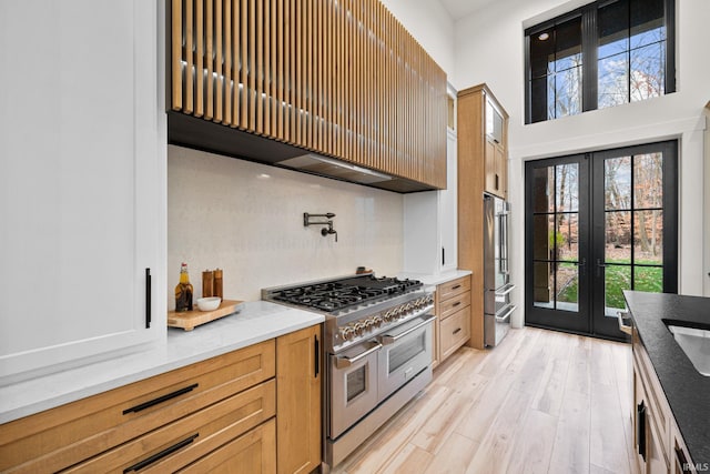 kitchen featuring high quality appliances, light wood-type flooring, a wealth of natural light, and french doors