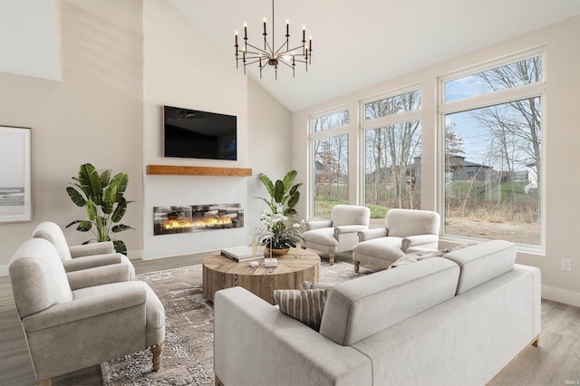 living room featuring an inviting chandelier, hardwood / wood-style flooring, high vaulted ceiling, and a healthy amount of sunlight