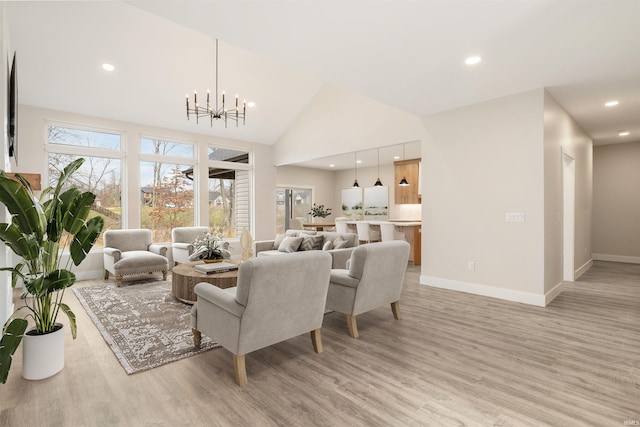 living room featuring a notable chandelier, high vaulted ceiling, and light hardwood / wood-style flooring