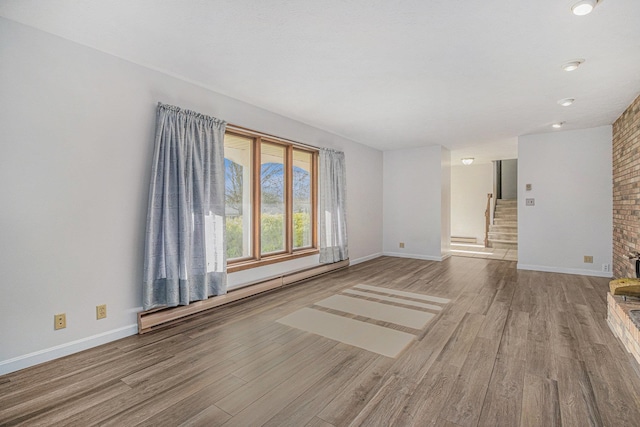 empty room featuring light wood-type flooring and a baseboard radiator