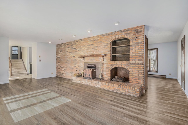 unfurnished living room with hardwood / wood-style floors, built in features, and a brick fireplace