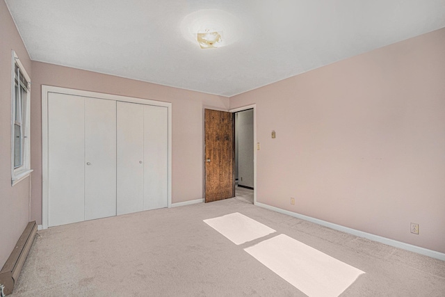 unfurnished bedroom featuring a baseboard heating unit, light carpet, and a closet