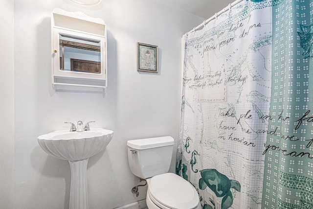 bathroom with toilet, curtained shower, and sink