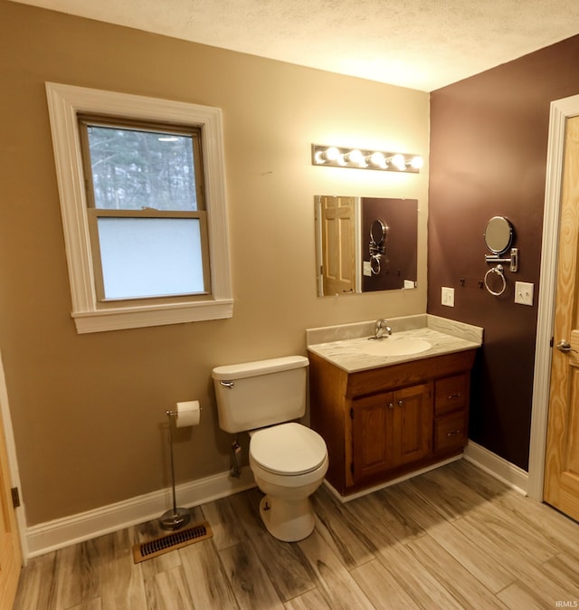 bathroom featuring toilet, vanity, a textured ceiling, and hardwood / wood-style flooring