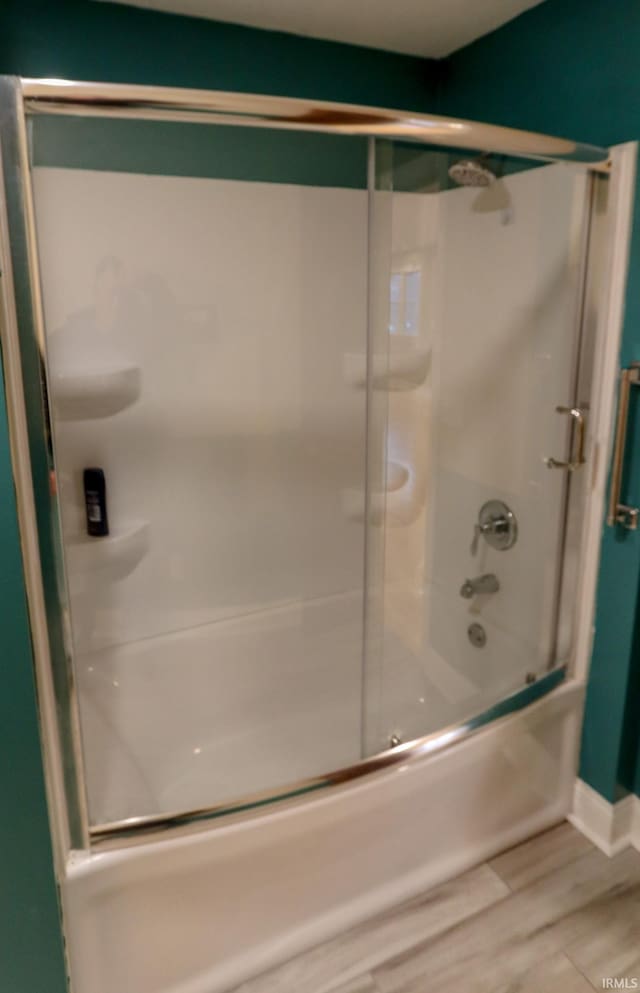 bathroom with hardwood / wood-style floors and bath / shower combo with glass door