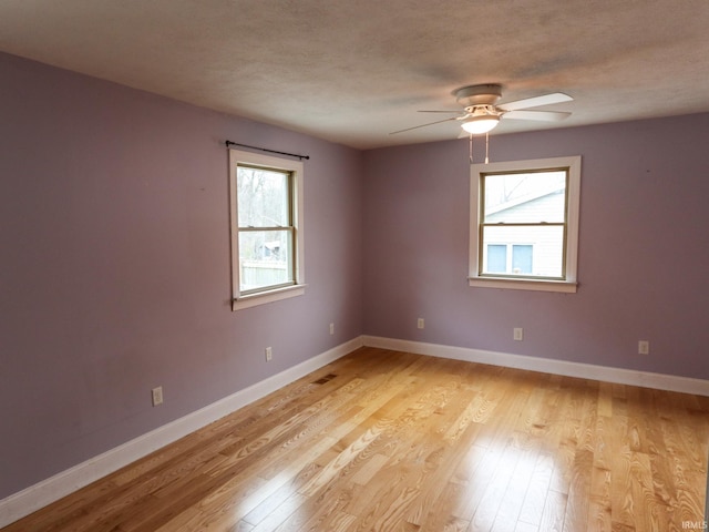 empty room with plenty of natural light, ceiling fan, and light hardwood / wood-style flooring