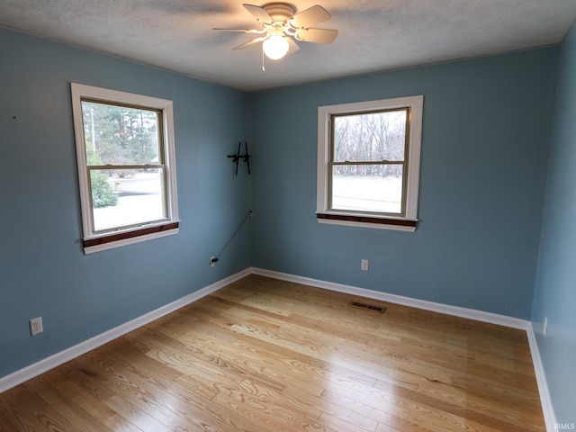 unfurnished room featuring a textured ceiling, light hardwood / wood-style flooring, ceiling fan, and a healthy amount of sunlight