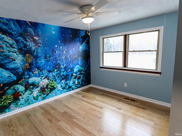 spare room with a textured ceiling, light hardwood / wood-style floors, and ceiling fan