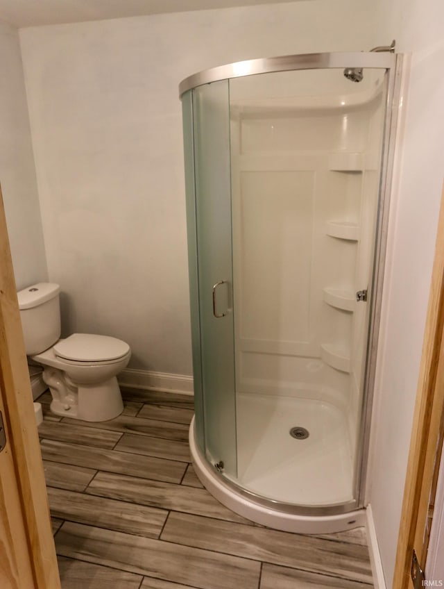 bathroom featuring hardwood / wood-style floors, a shower with door, and toilet