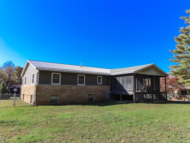 rear view of property with a sunroom and a lawn