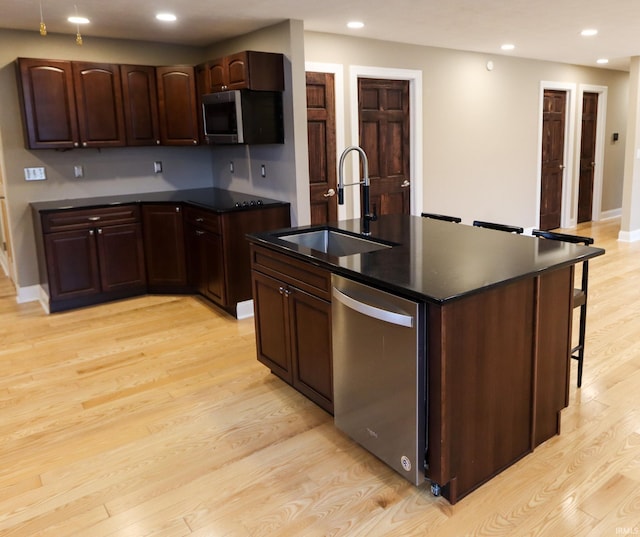 kitchen with an island with sink, stainless steel appliances, light hardwood / wood-style floors, and sink