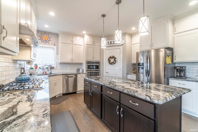 kitchen with dark brown cabinetry, a kitchen island, light hardwood / wood-style floors, white cabinets, and appliances with stainless steel finishes