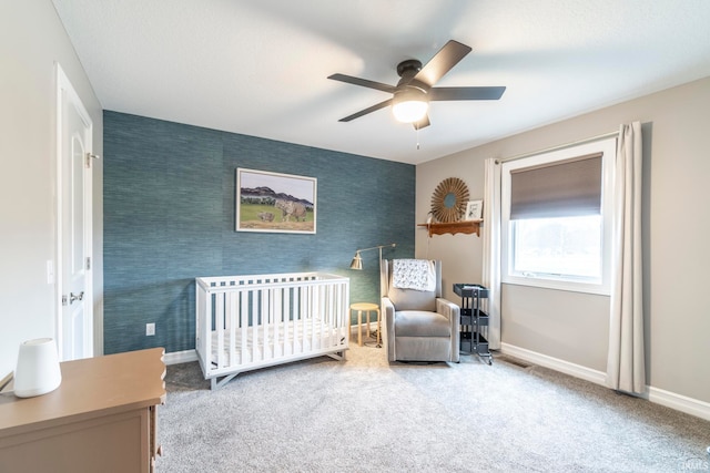 bedroom with carpet flooring, ceiling fan, and a crib