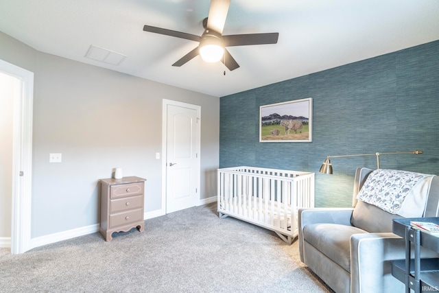 bedroom featuring carpet, ceiling fan, and a nursery area