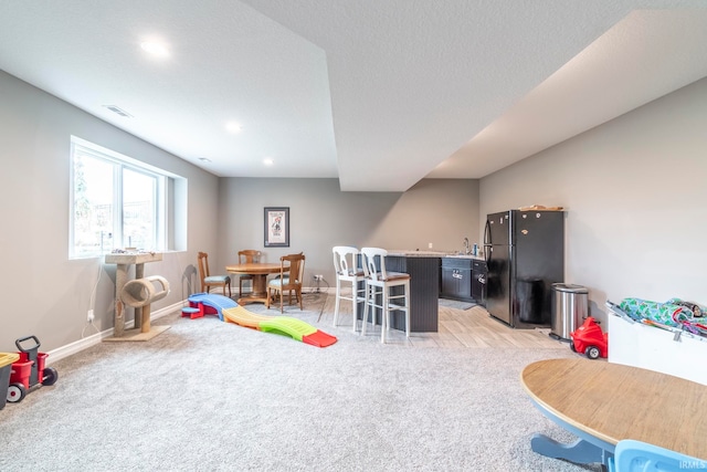 rec room featuring a textured ceiling and light colored carpet