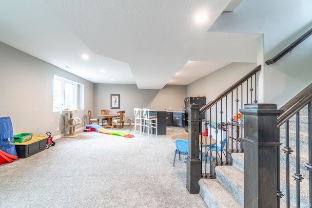 recreation room featuring carpet and a textured ceiling