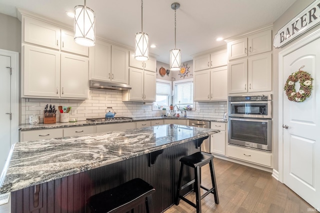 kitchen featuring light stone countertops, wood-type flooring, backsplash, and white cabinets