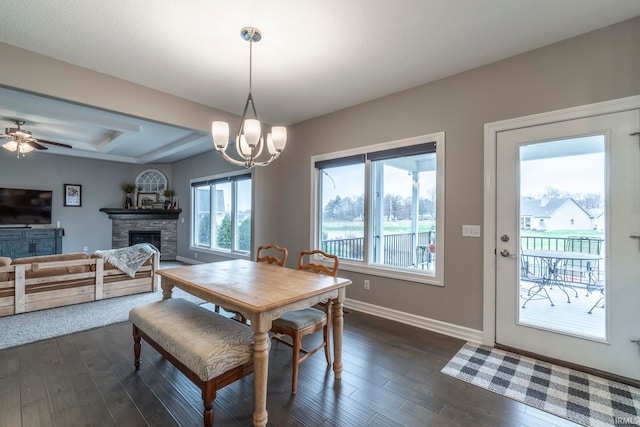 dining room featuring a fireplace, dark wood-type flooring, and ceiling fan with notable chandelier