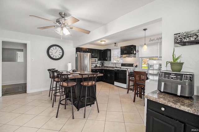 kitchen with pendant lighting, a kitchen breakfast bar, light tile patterned floors, appliances with stainless steel finishes, and a kitchen island