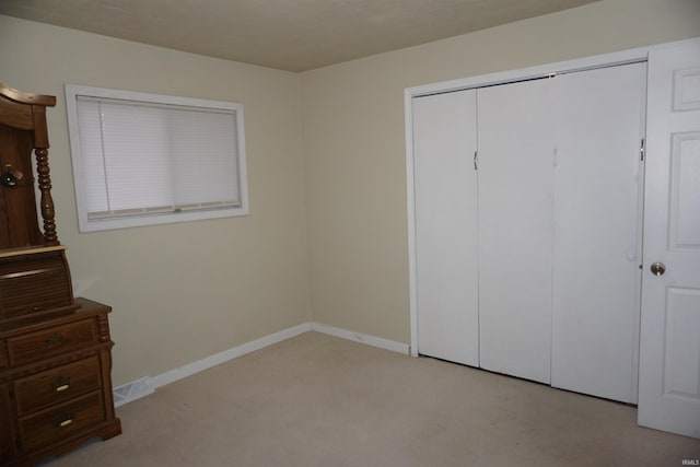 unfurnished bedroom with light carpet and a closet