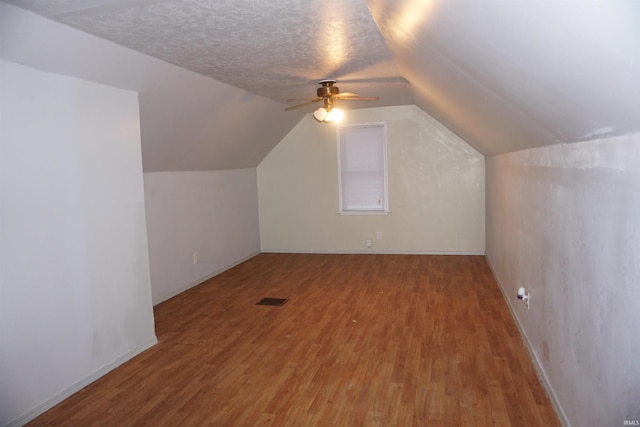 bonus room featuring hardwood / wood-style floors, ceiling fan, lofted ceiling, and a textured ceiling