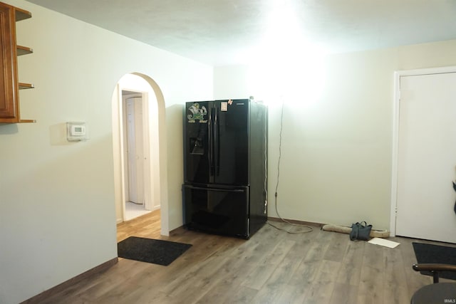 interior space featuring light hardwood / wood-style floors and black fridge with ice dispenser