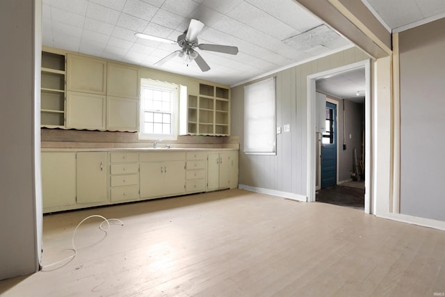 kitchen featuring ornamental molding, ceiling fan, sink, cream cabinets, and light hardwood / wood-style floors