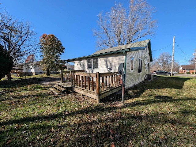 rear view of house with central air condition unit, a lawn, and a wooden deck