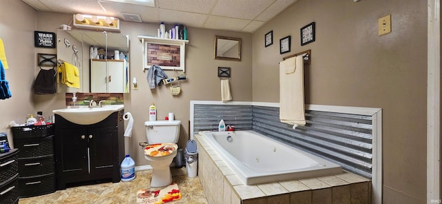 bathroom featuring vanity, toilet, a drop ceiling, and tiled tub