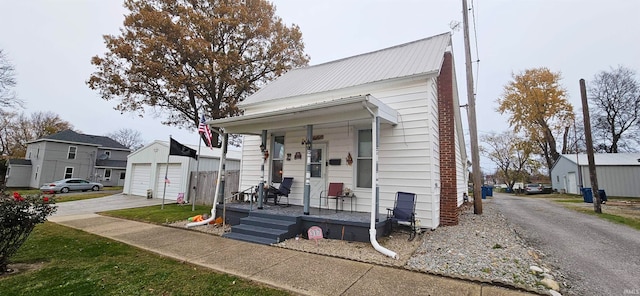 bungalow-style house featuring a porch, a garage, and an outbuilding