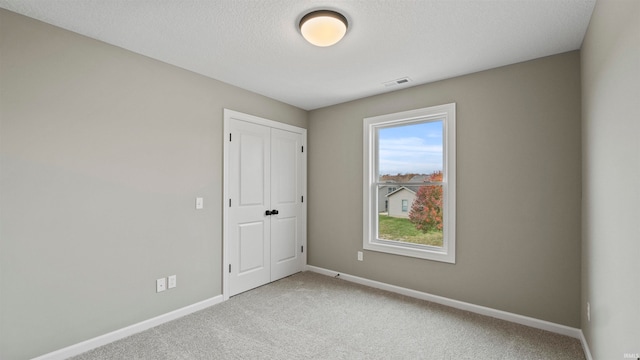 unfurnished room featuring light colored carpet and a textured ceiling