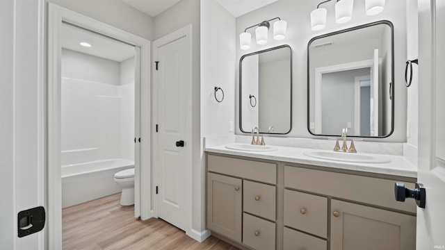 full bathroom featuring wood-type flooring, vanity, toilet, and  shower combination