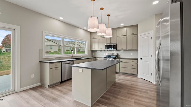 kitchen featuring a kitchen island, a healthy amount of sunlight, stainless steel appliances, and hanging light fixtures