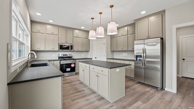 kitchen featuring pendant lighting, sink, light hardwood / wood-style floors, appliances with stainless steel finishes, and a kitchen island