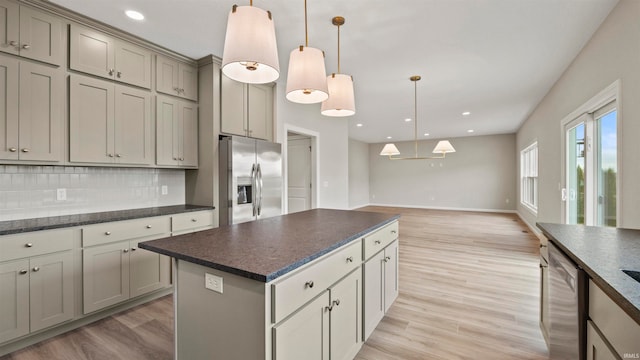 kitchen with a center island, backsplash, hanging light fixtures, light hardwood / wood-style flooring, and stainless steel appliances