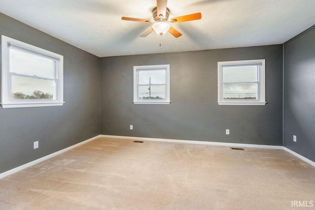 carpeted empty room with ceiling fan and a healthy amount of sunlight