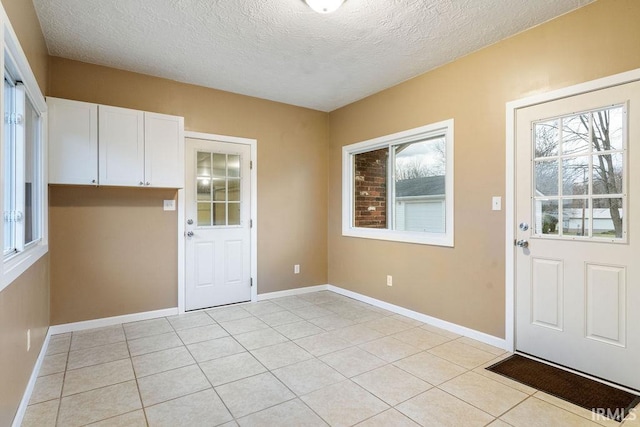 entryway featuring light tile patterned floors, a textured ceiling, and plenty of natural light