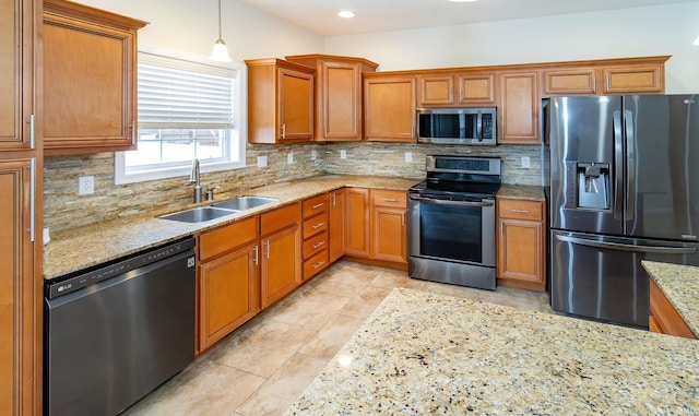 kitchen featuring light stone countertops, sink, pendant lighting, decorative backsplash, and appliances with stainless steel finishes