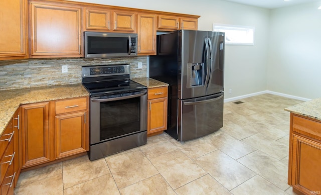 kitchen featuring backsplash, light stone counters, light tile patterned flooring, and stainless steel appliances