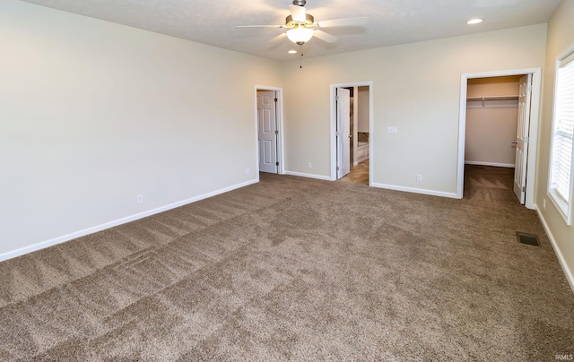 unfurnished bedroom featuring ceiling fan, a closet, carpet, and a spacious closet