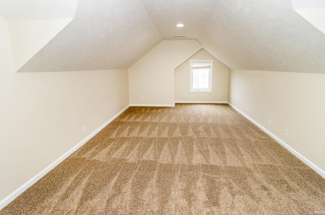 additional living space with light colored carpet, lofted ceiling, and a textured ceiling