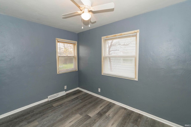 empty room with dark hardwood / wood-style floors, ceiling fan, and a wealth of natural light