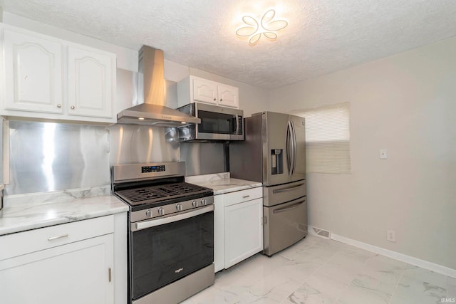 kitchen with white cabinetry, light stone countertops, wall chimney exhaust hood, a textured ceiling, and appliances with stainless steel finishes