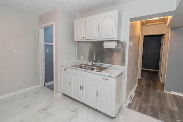 kitchen with light stone countertops, white cabinets, light hardwood / wood-style floors, and a textured ceiling