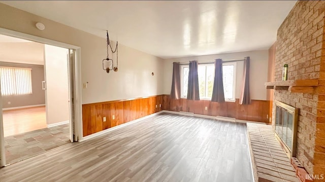 unfurnished living room with a fireplace, hardwood / wood-style floors, and wooden walls