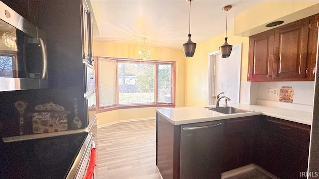 kitchen with sink, hanging light fixtures, kitchen peninsula, a chandelier, and light hardwood / wood-style floors