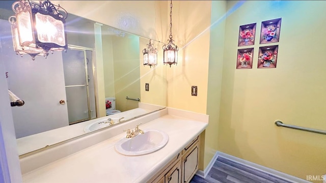 bathroom featuring hardwood / wood-style floors, vanity, a shower with door, and toilet