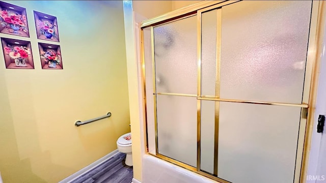 bathroom with toilet, enclosed tub / shower combo, and wood-type flooring