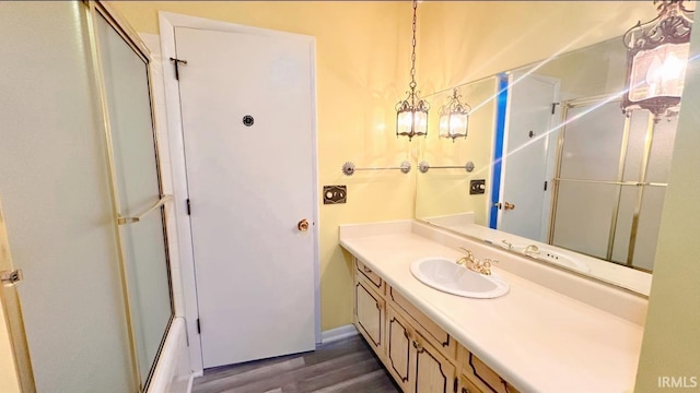 bathroom featuring hardwood / wood-style flooring, vanity, and enclosed tub / shower combo