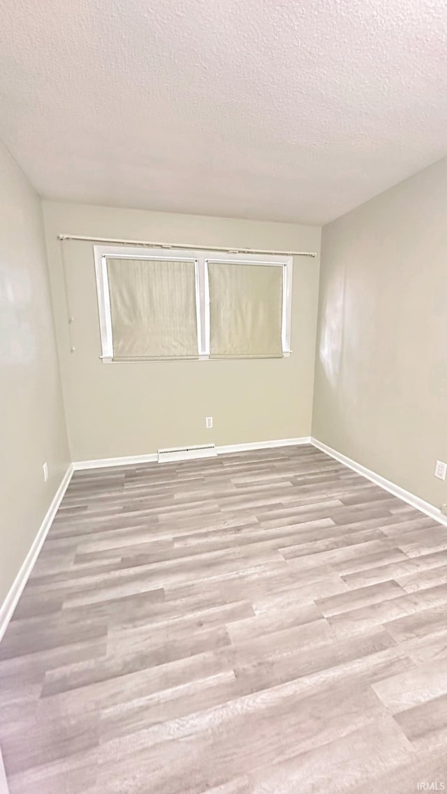 spare room featuring light hardwood / wood-style floors and a textured ceiling